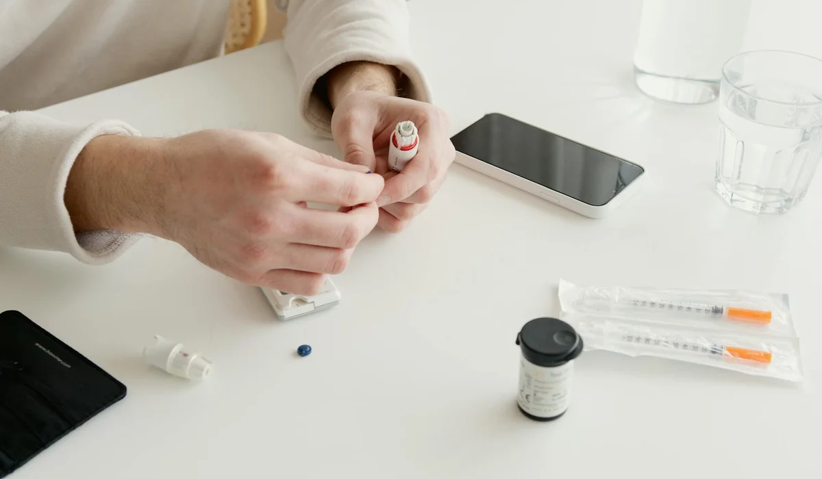 Person preparing an aquarium water test kit on a clean desk, with test tubes, a small bottle, a smartphone, and a dropper visible.