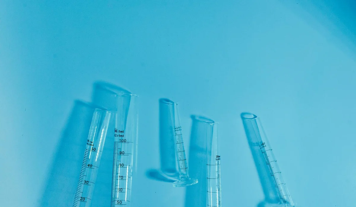 Blue-tinted image of glass test tubes and graduated cylinders standing upright, symbolizing CO2 equipment for planted aquariums.
