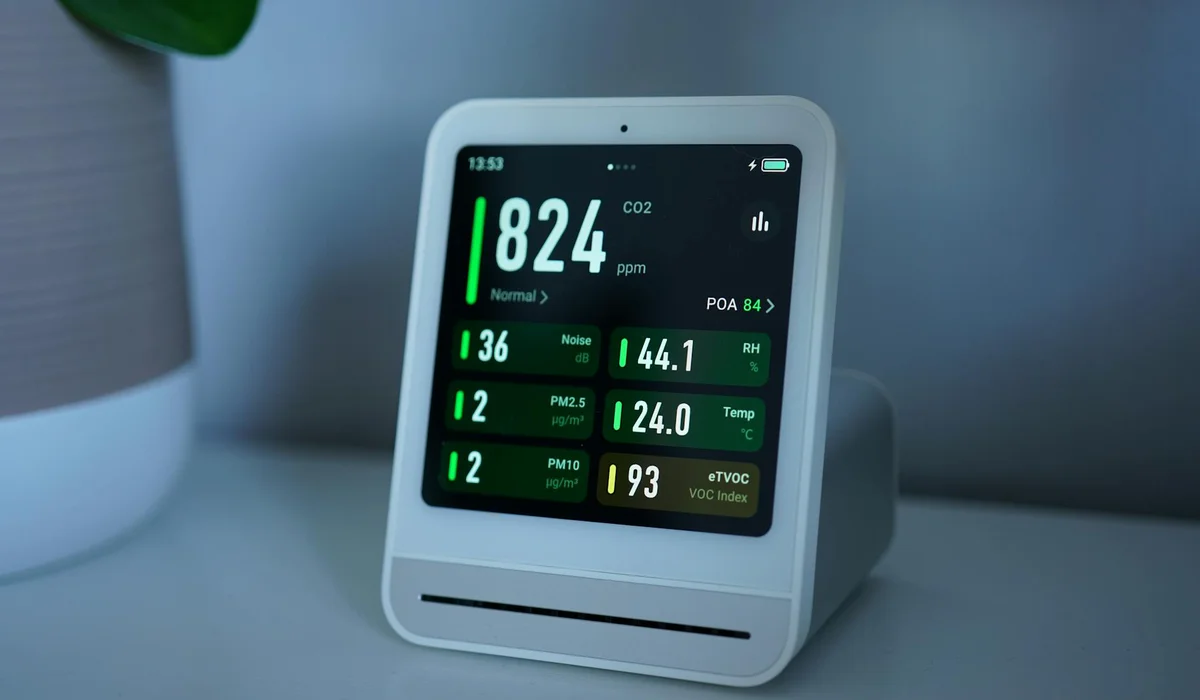 A compact CO2 monitoring device on a white stand displaying real-time CO2 ppm and other aquarium parameters
