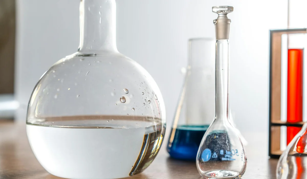 Laboratory glassware with water, including a round-bottom flask and an Erlenmeyer, illustrating water treatment for aquariums