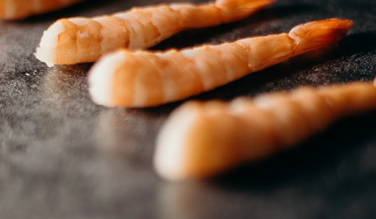 Close-up of pale freshwater shrimp tails on a dark surface.