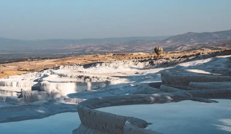 White travertine terraces with blue pools and a distant landscape