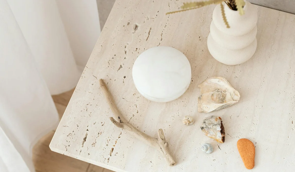 Assorted driftwood pieces and natural decor laid out on a light surface, including a white round stone and a small white vase in the background.