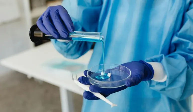 Lab technician wearing blue gloves tests water samples with a pipette and a petri dish