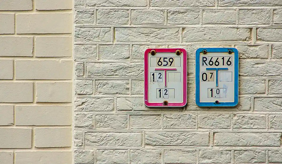 Two colorful aquarium water testing kits mounted on a white brick wall.