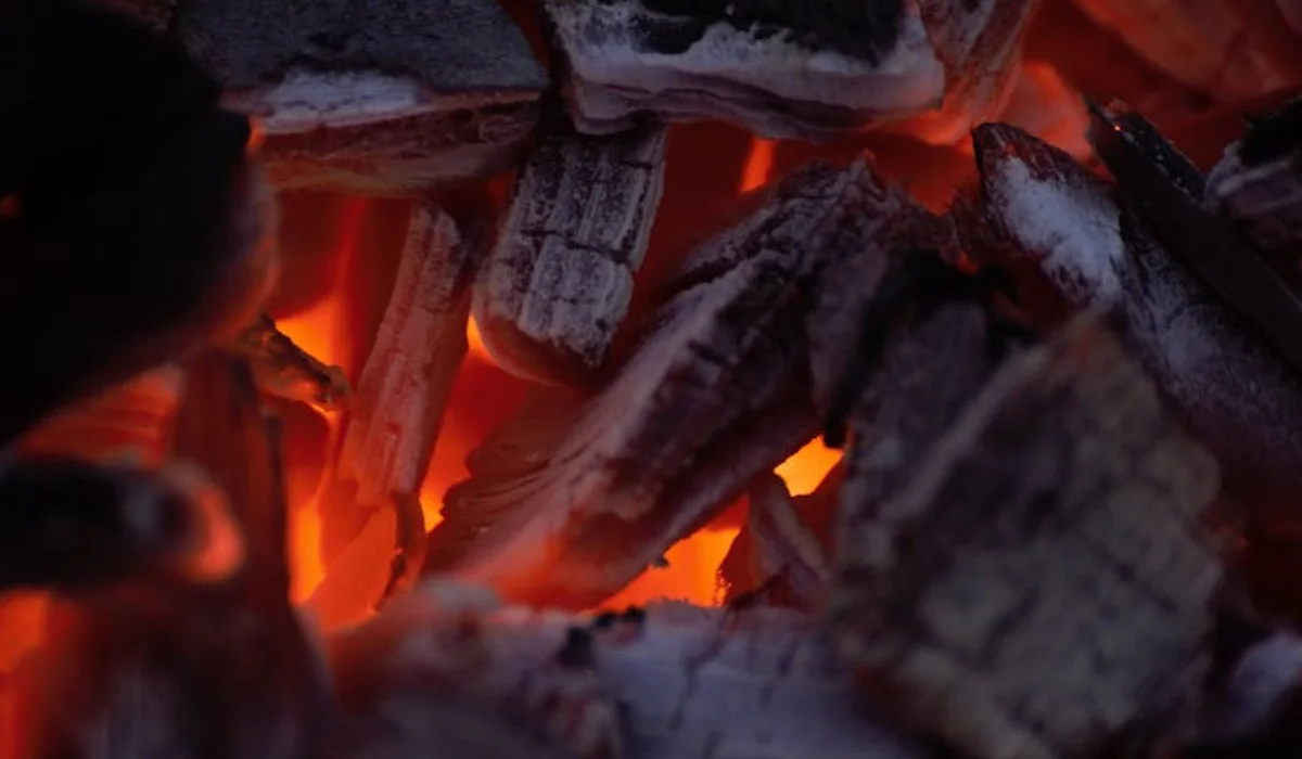 Close-up of glowing charcoal embers with orange-red heat