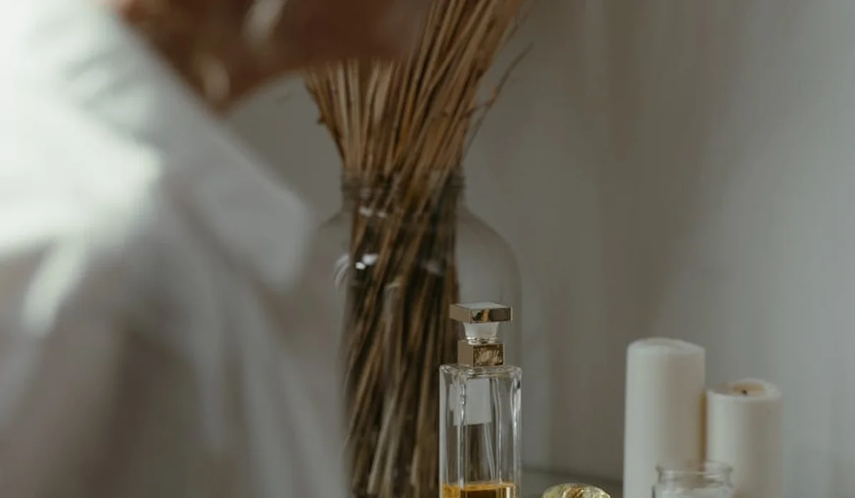 Close-up of a glass bottle containing a fermentation solution for a DIY yeast-and-sugar CO2 system, with tubing visible in the background and a blurred figure in a white lab coat.