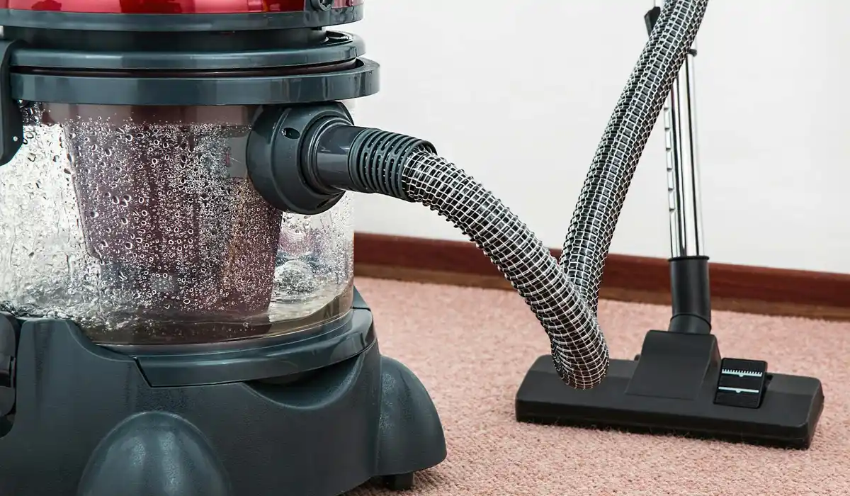 Close-up of a gravel vacuum connected to an aquarium filter with a flexible hose, showing the cleaning gear ready for use