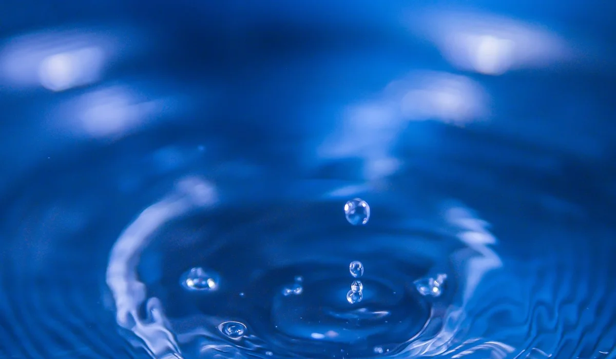 Close-up of blue aquarium water with bubbles rising from the surface, illustrating dissolved oxygen in fish tanks.
