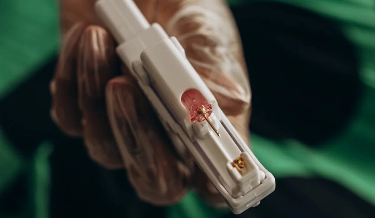 Close-up of a gloved hand holding an aquarium water testing device with color-changing indicator wells.