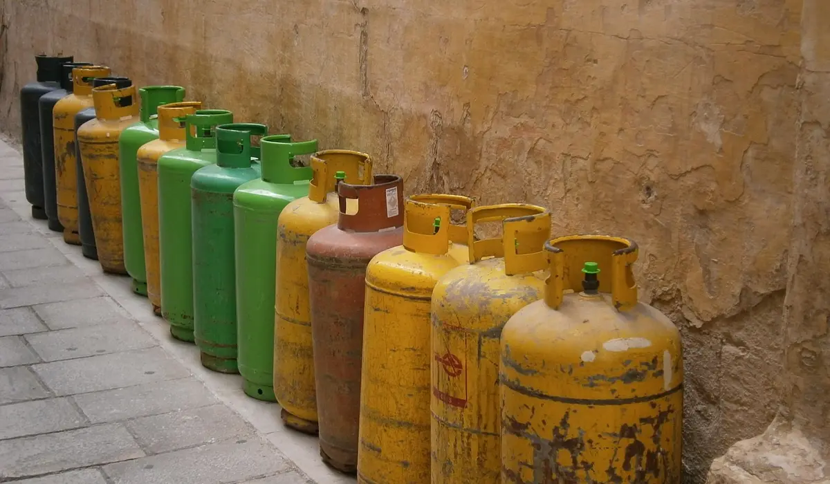 Row of yellow and green CO2 gas cylinders lined up along a concrete wall