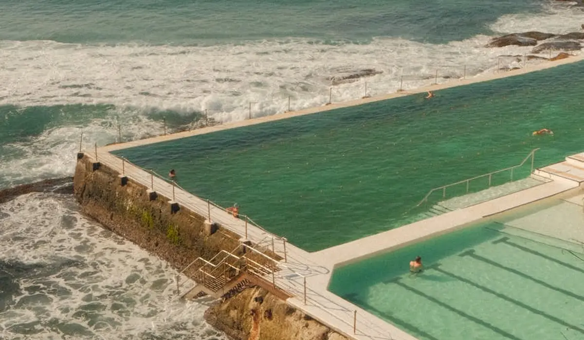 Overhead view of a coastal swimming pool beside the ocean, used as a visual metaphor for varying water sources and the care required for aquarium water.