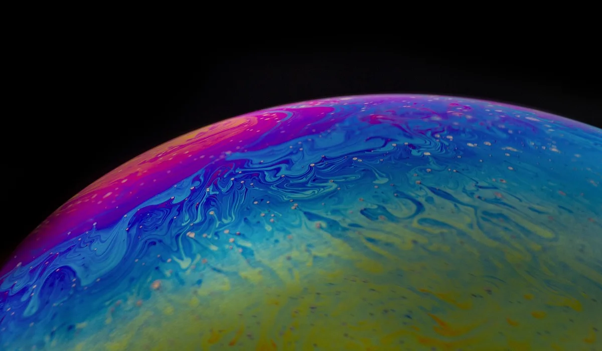 Close-up of a multicolored bubble with swirling rainbow patterns against a black background.