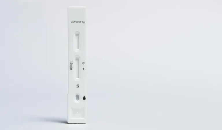 Vertical white COVID-19 rapid test kit on a clean white surface.