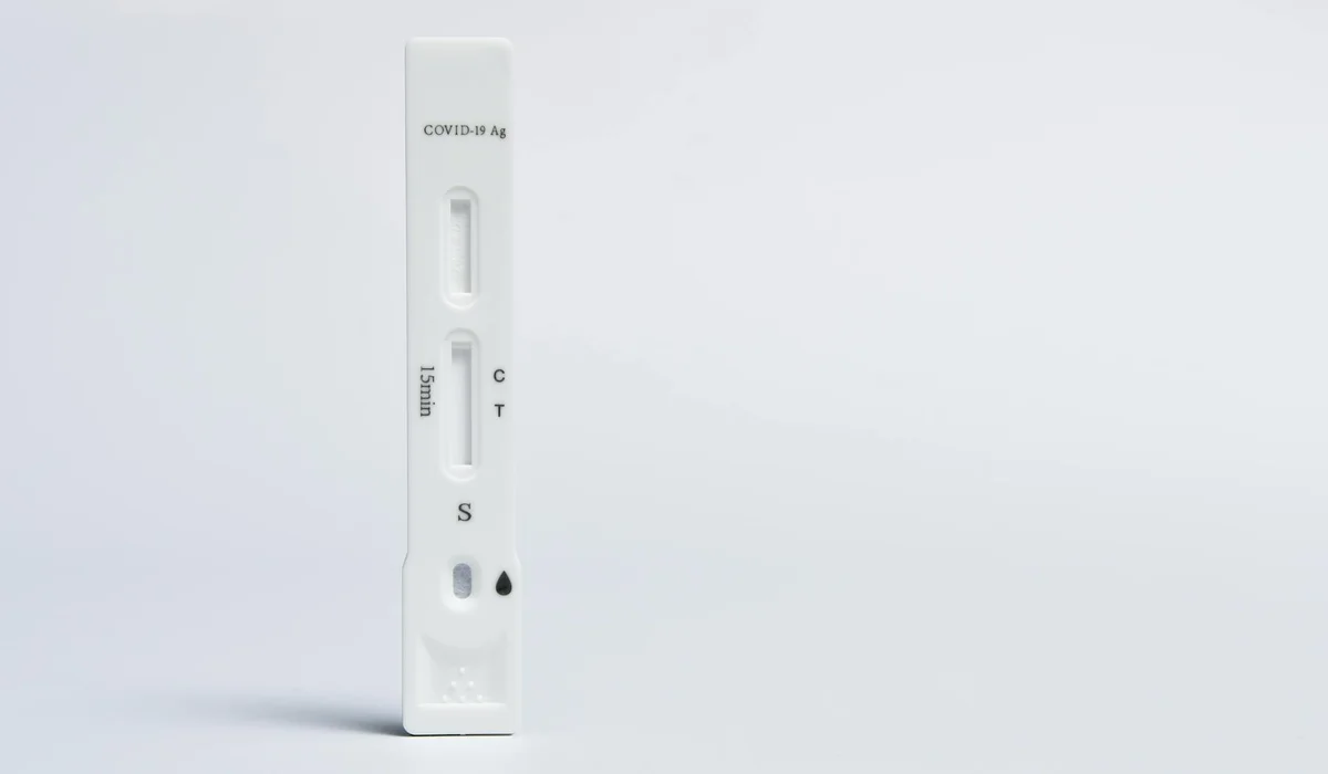 Vertical white COVID-19 rapid test kit on a clean white surface.