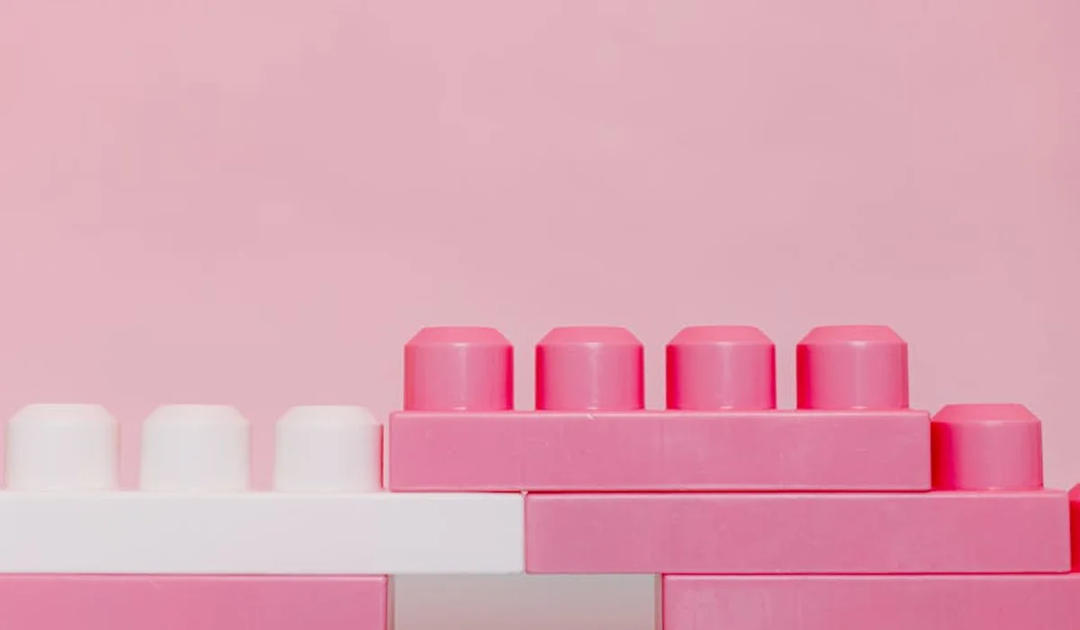 Pastel pink LEGO bricks stacked against a soft pink background