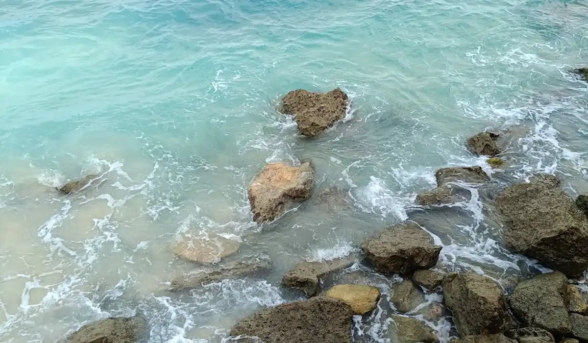 Rocky shoreline with turquoise water and large brown rocks along the edge.