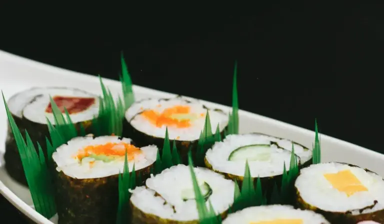 Assorted sushi rolls on a white platter with green garnish, illustrating portion control